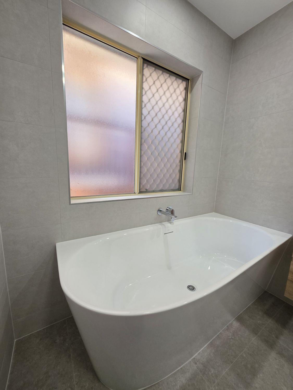 Freestanding white bath and wall-mounted tapware in the completed Bellbowrie bathroom