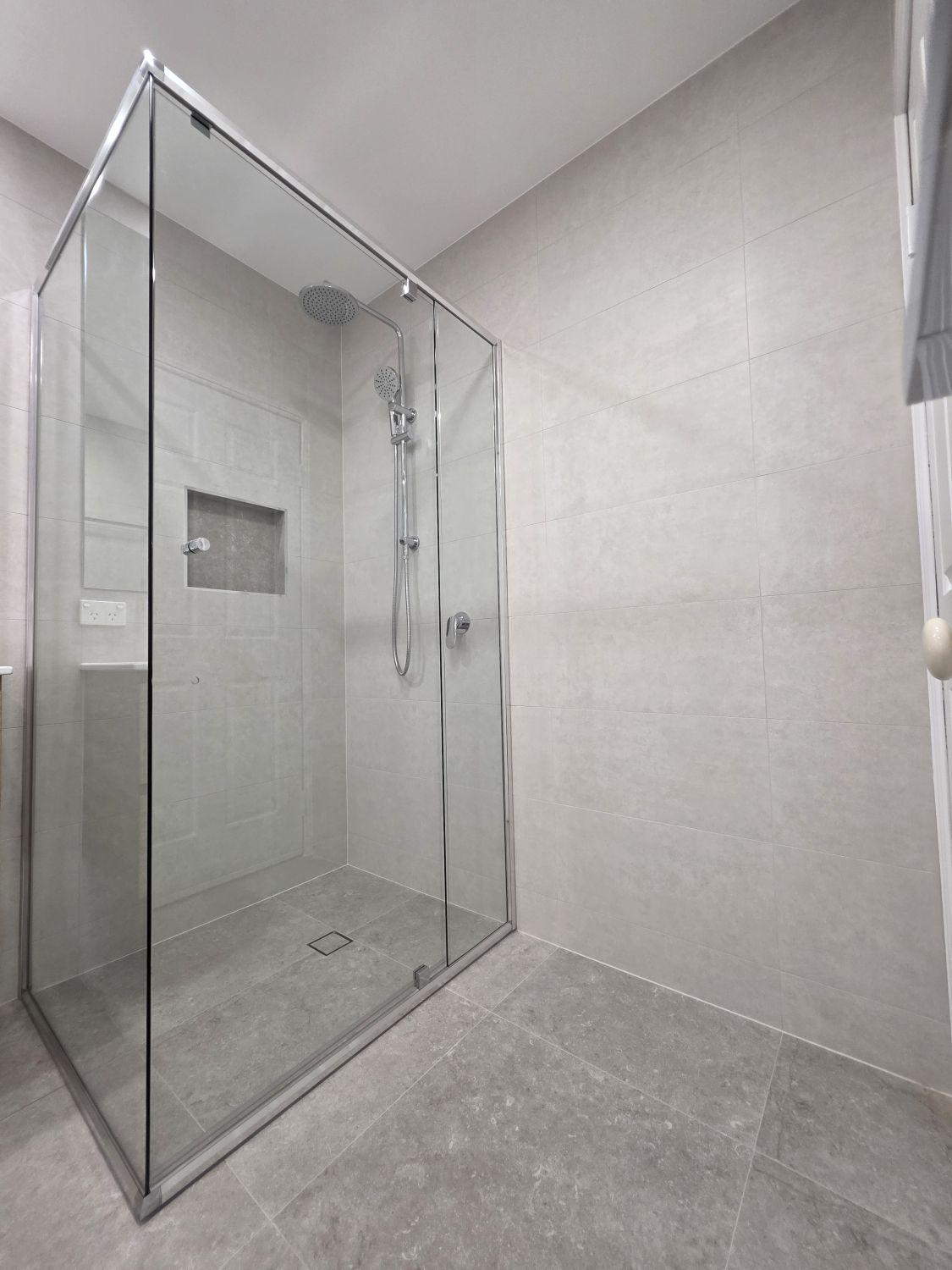 Large glass shower with rain head, hand shower and recessed niche in Bellbowrie