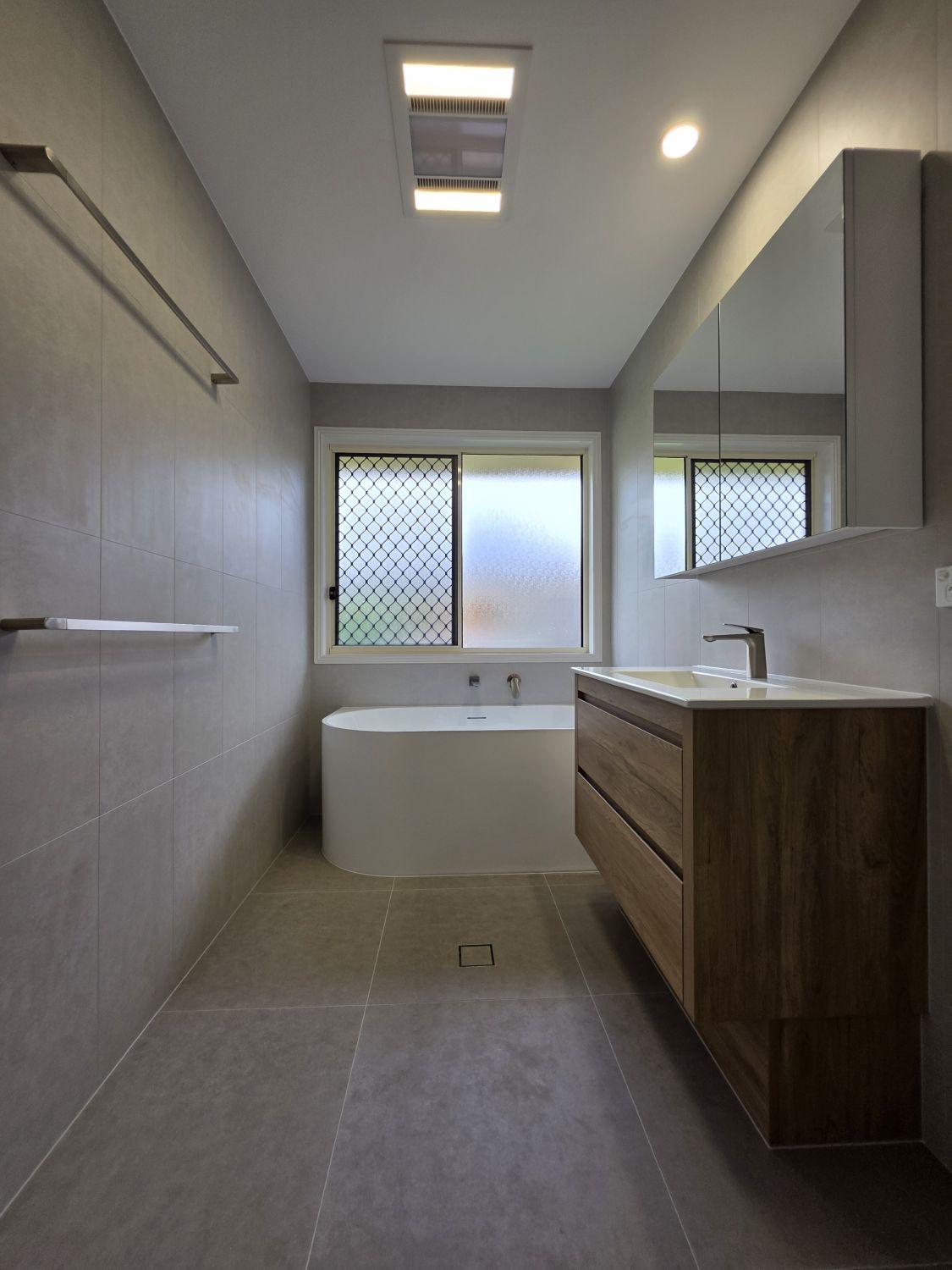 Completed North Lakes main bathroom with curved bath and timber-look vanity