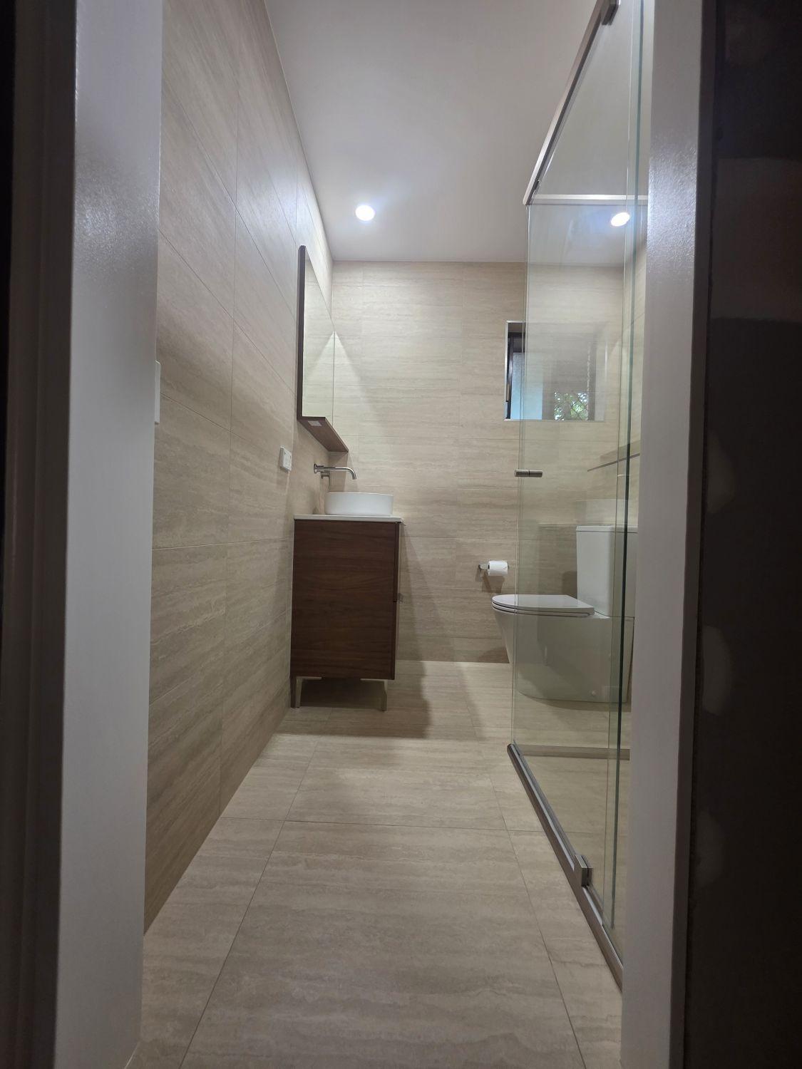 Wishart downstairs bathroom after renovation with full-height tile, glass shower and compact vanity