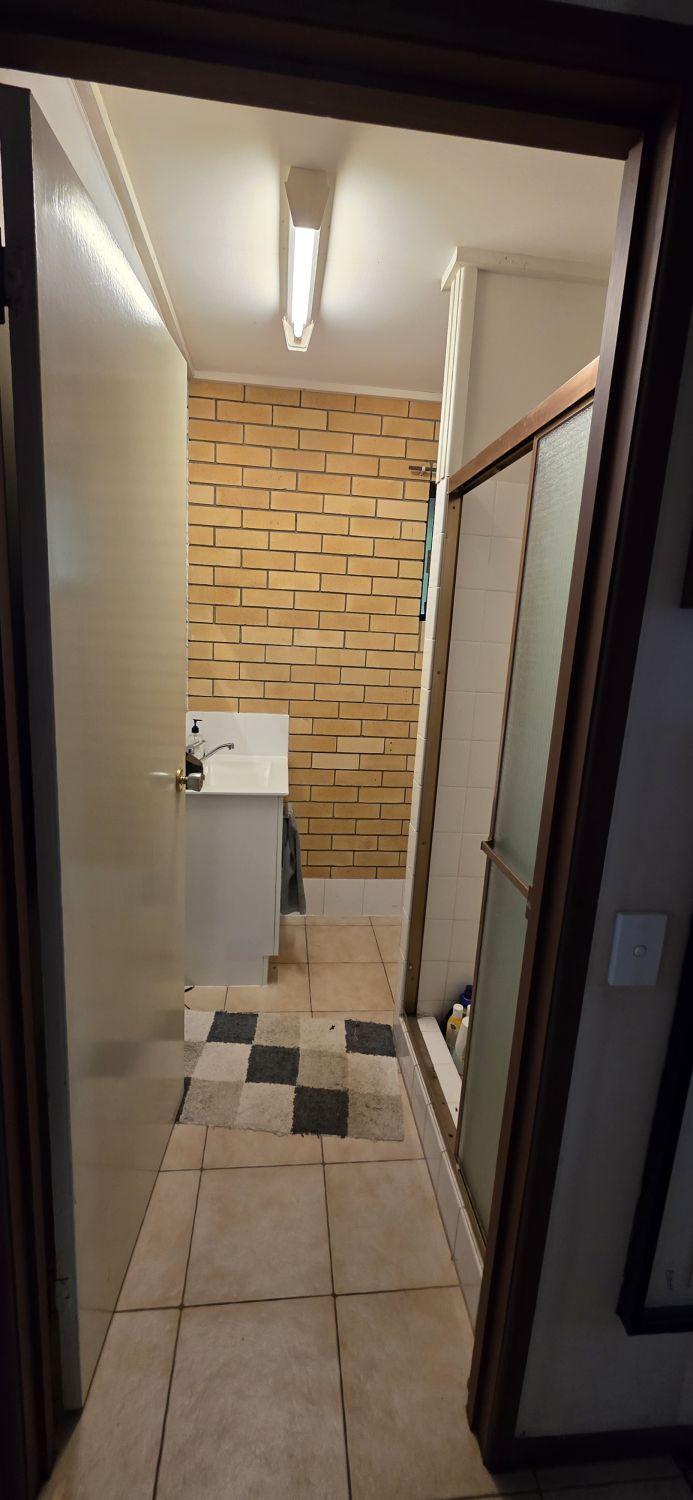 Wishart downstairs bathroom before renovation with exposed brick wall and framed shower