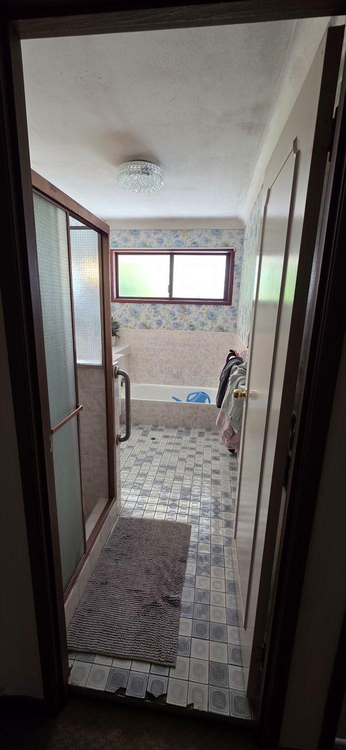 Wishart upstairs main bathroom before renovation with patterned flooring and enclosed shower