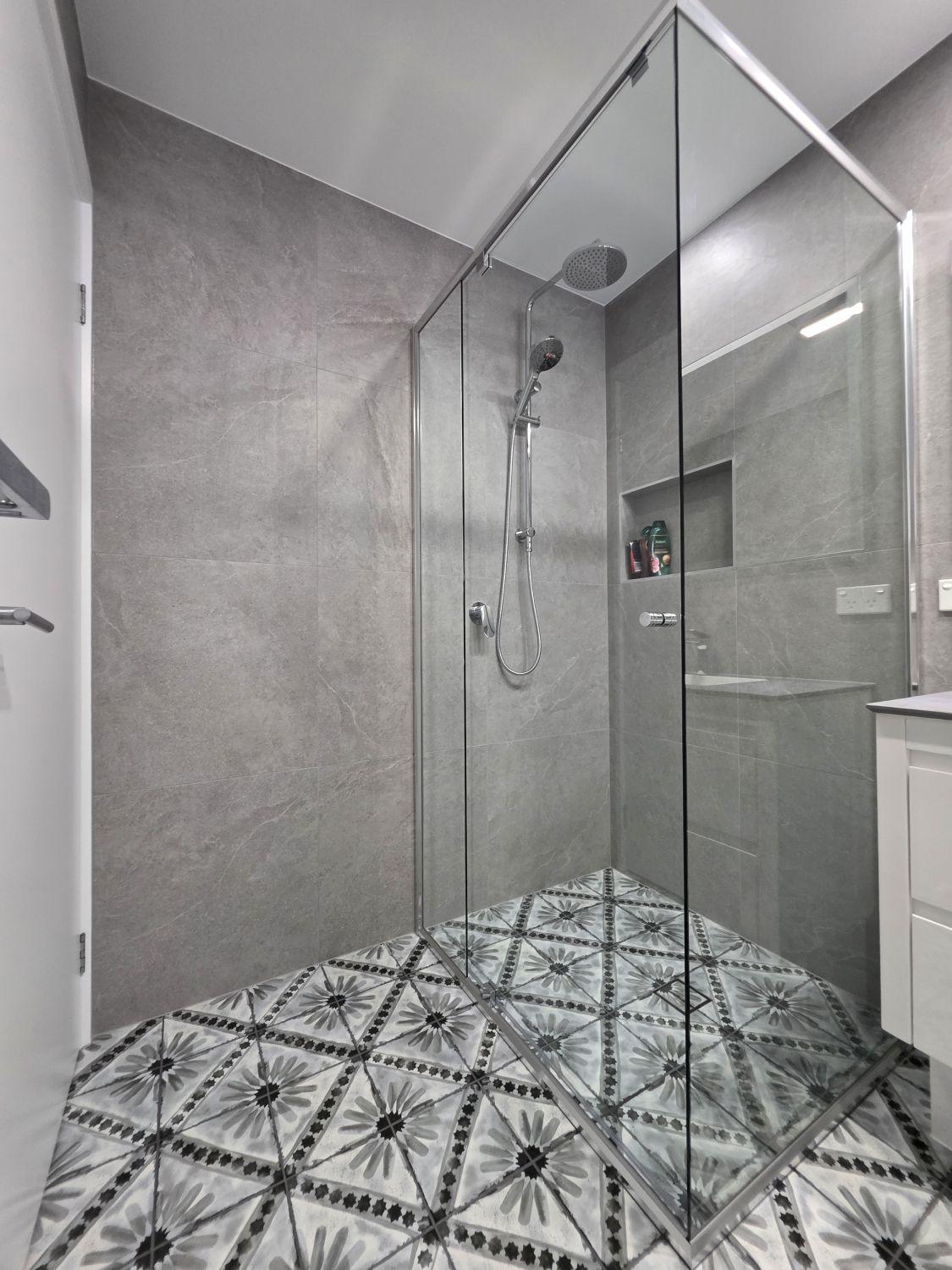Open glass shower with rain head and recessed niche in the completed Augustine Heights bathroom