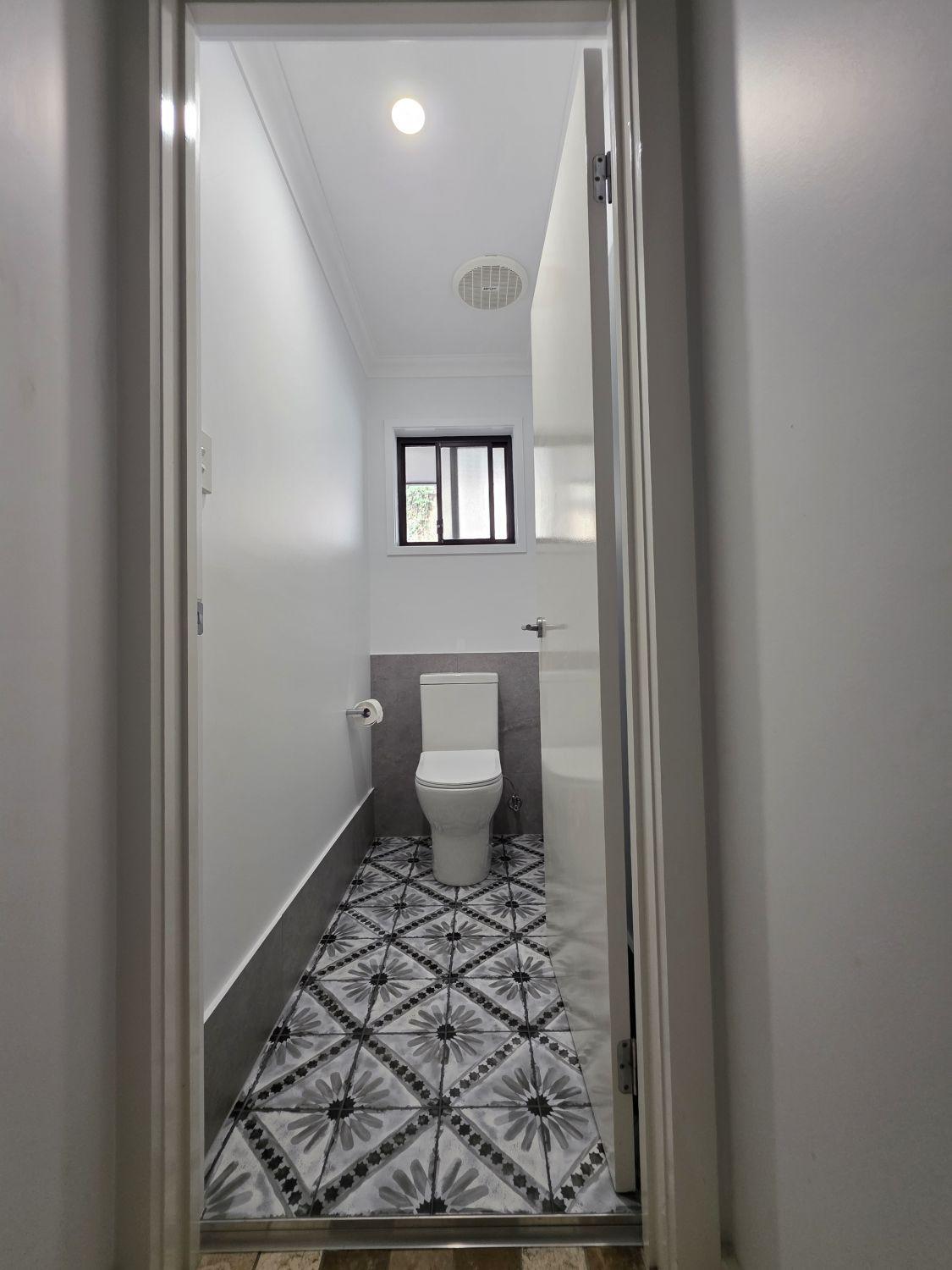Separate Augustine Heights toilet after renovation with patterned floor tile