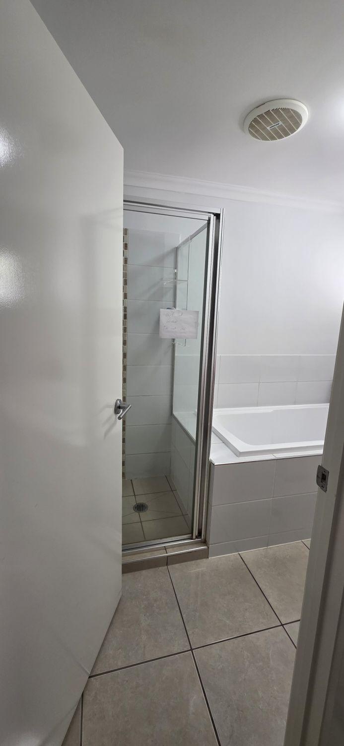 Augustine Heights bathroom entrance before renovation with framed shower and built-in bath