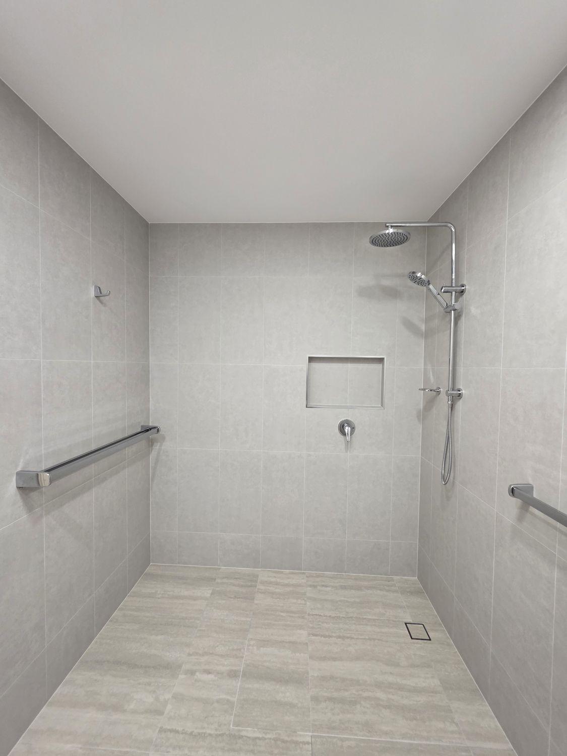 Large open level-entry shower with dual fittings and recessed niche in Bardon