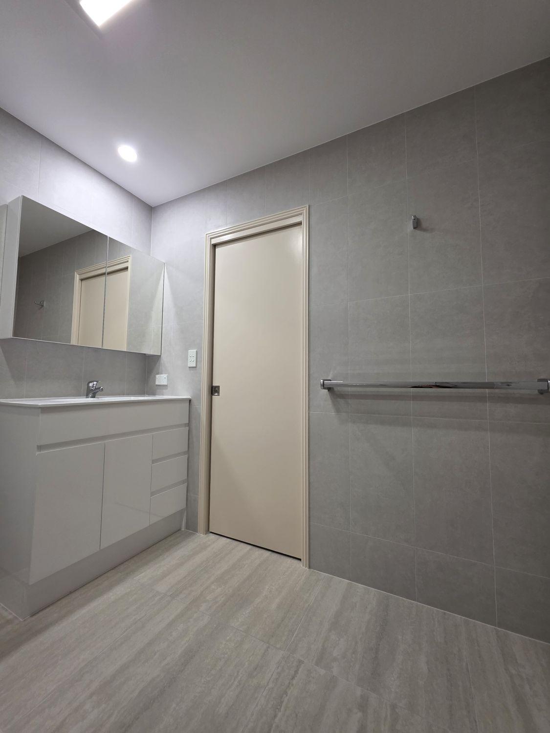 Full-height grey tile and long support rail beside the vanity in Bardon