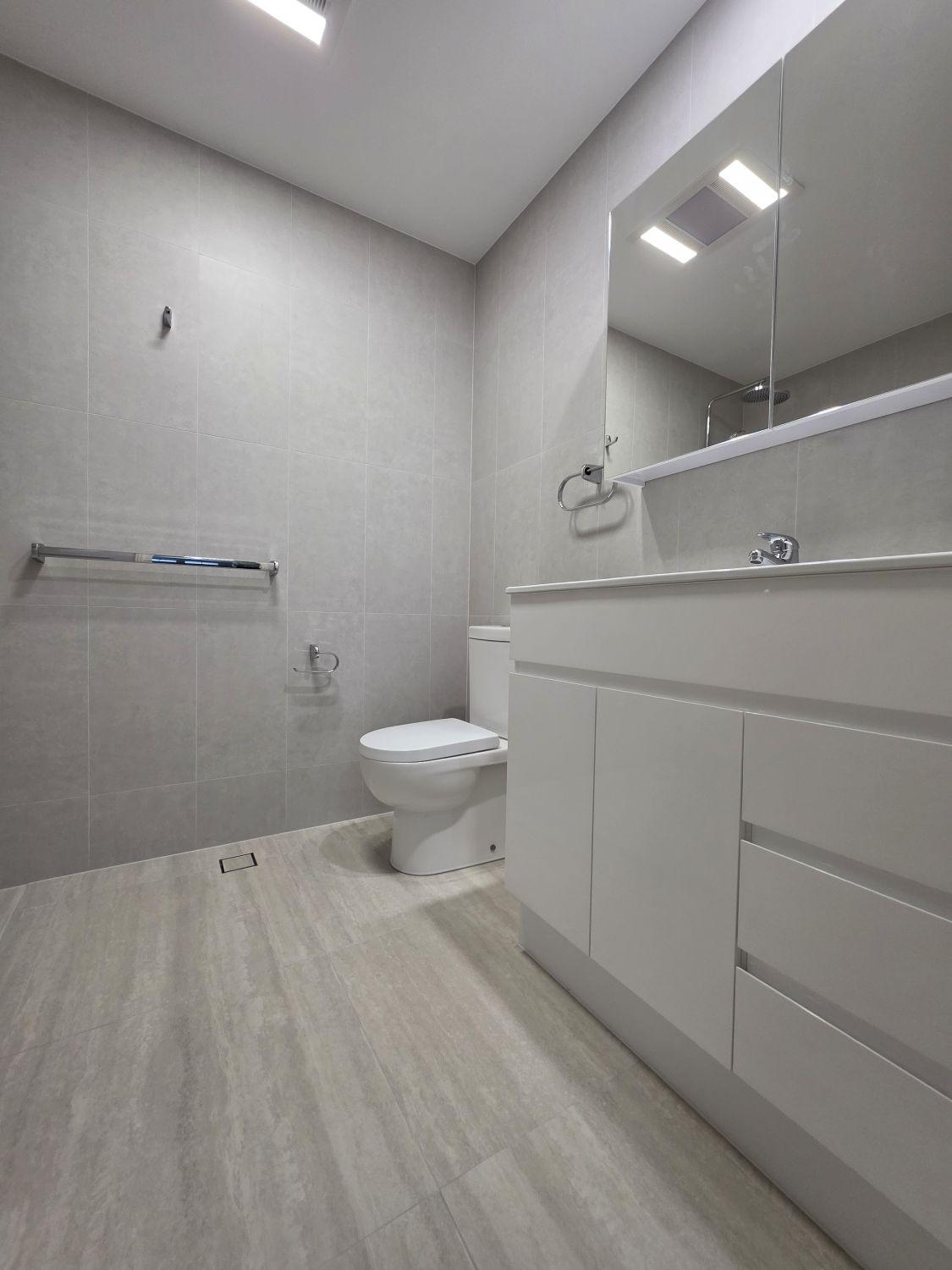 Wide white vanity and mirrored storage in the completed Bardon bathroom