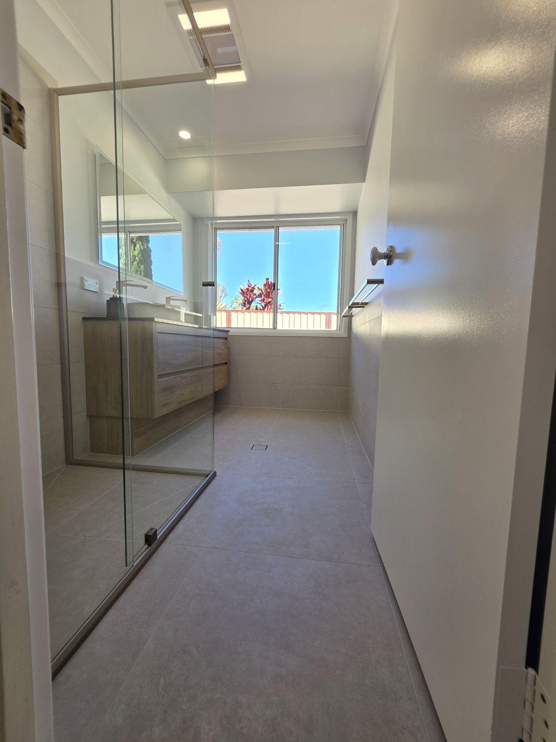 Calamvale bathroom entrance after renovation with open floor and glass shower