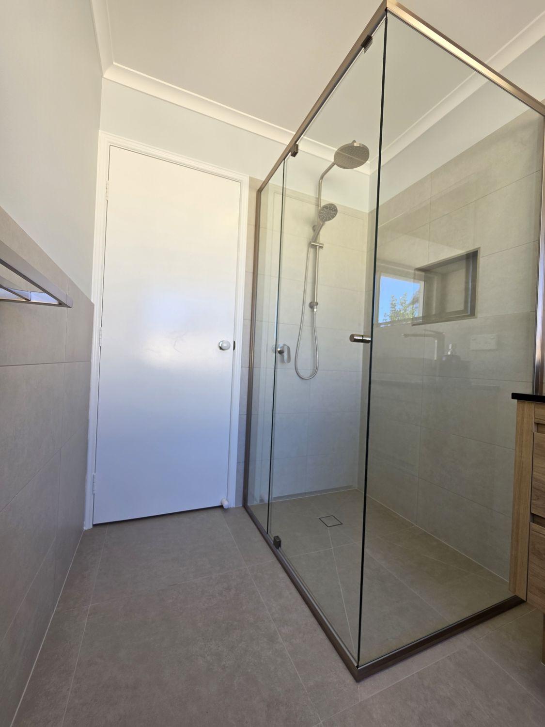 Large glass shower with rain head and hand shower in the renovated Calamvale bathroom