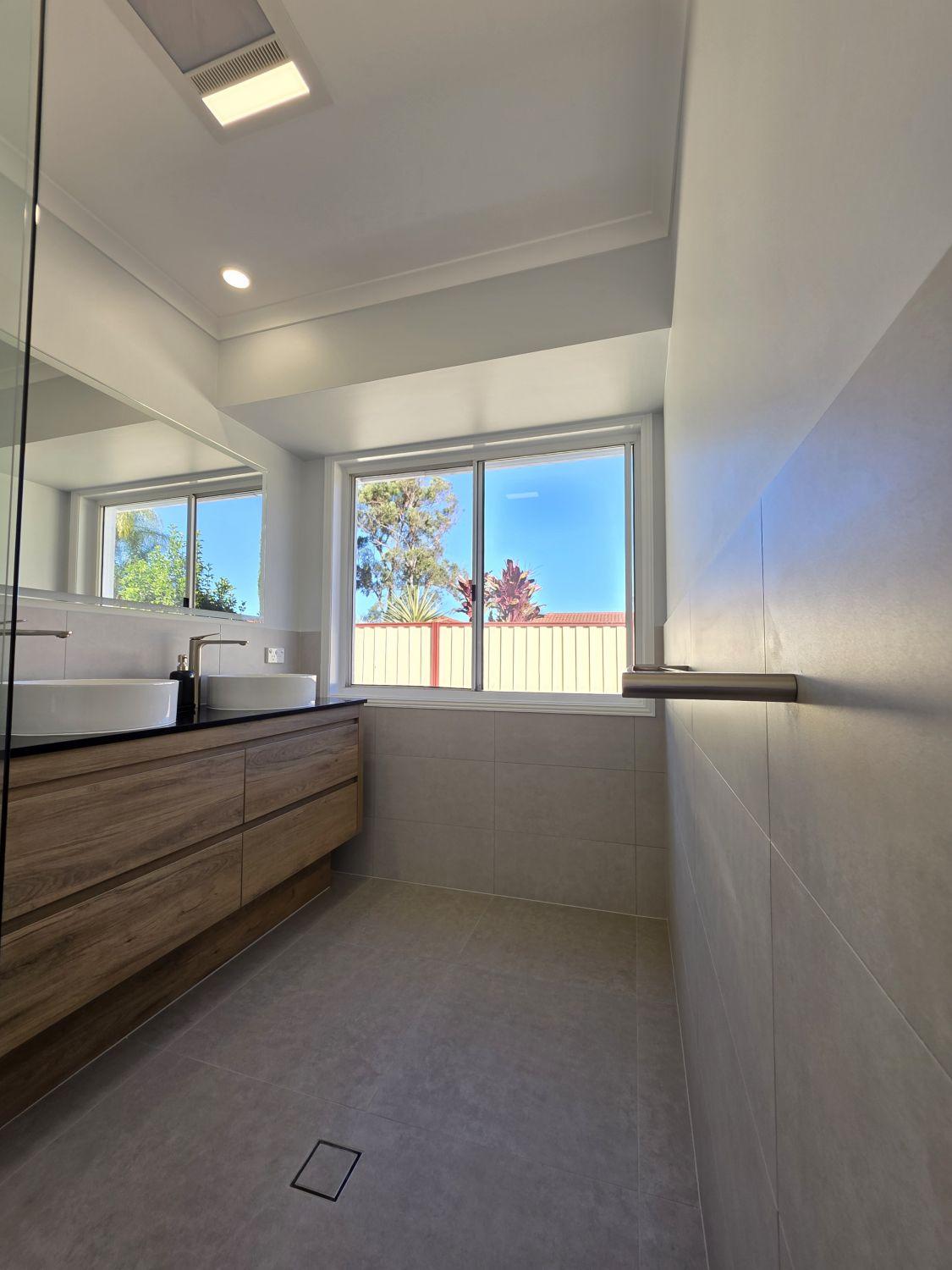 Wide timber-look double vanity below a broad mirror in the completed Calamvale bathroom