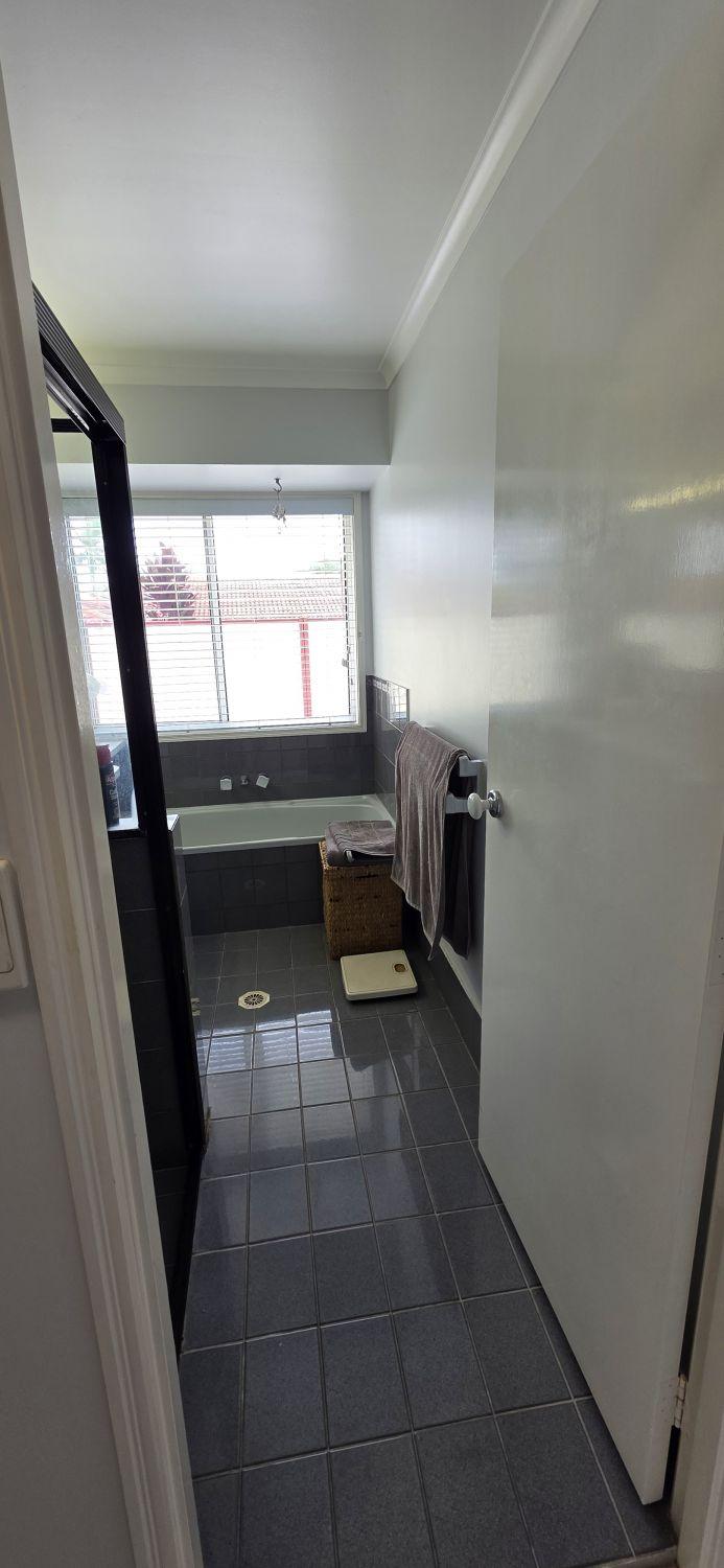 Calamvale bathroom entrance before renovation with dark floor tiles and built-in bath