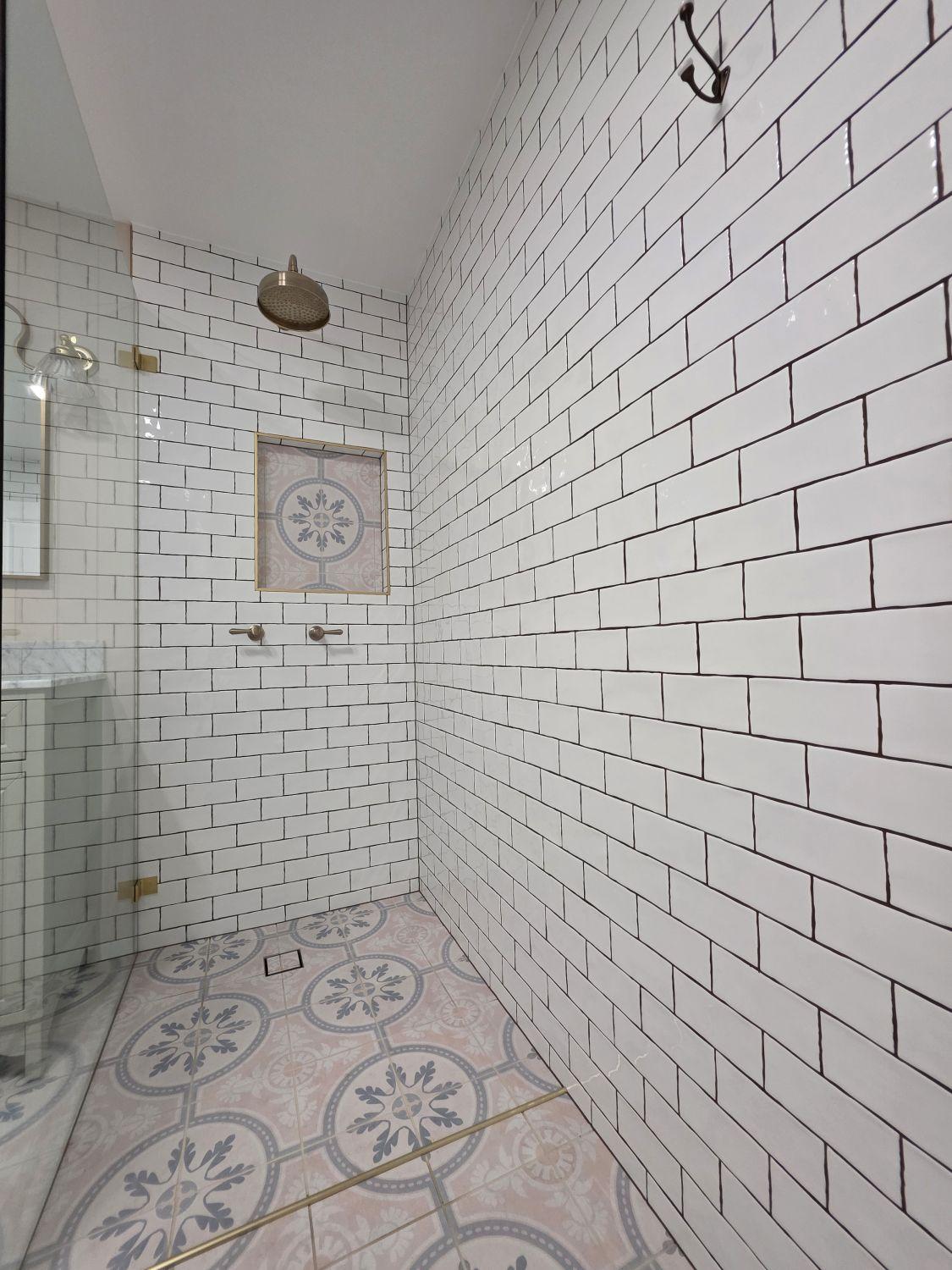 Open walk-in shower with brass fittings and patterned floor in Holland Park