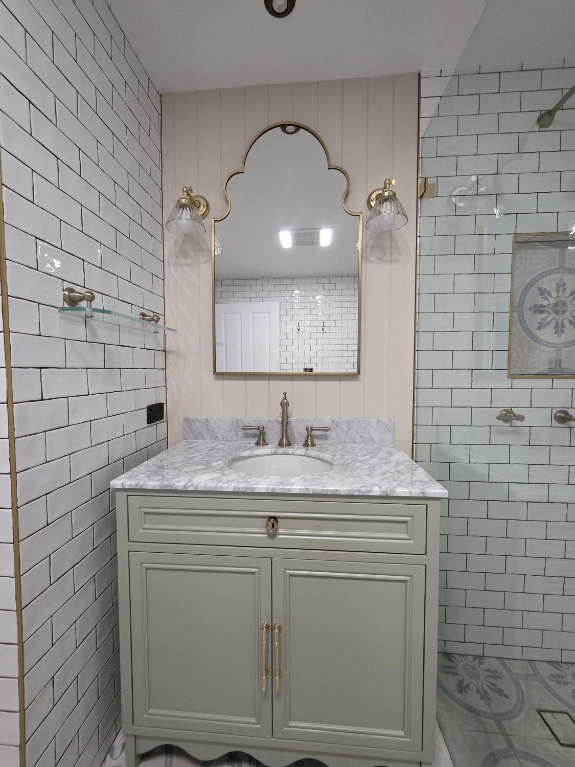 Furniture-style vanity with marble-look top and shaped mirror in the completed Holland Park bathroom