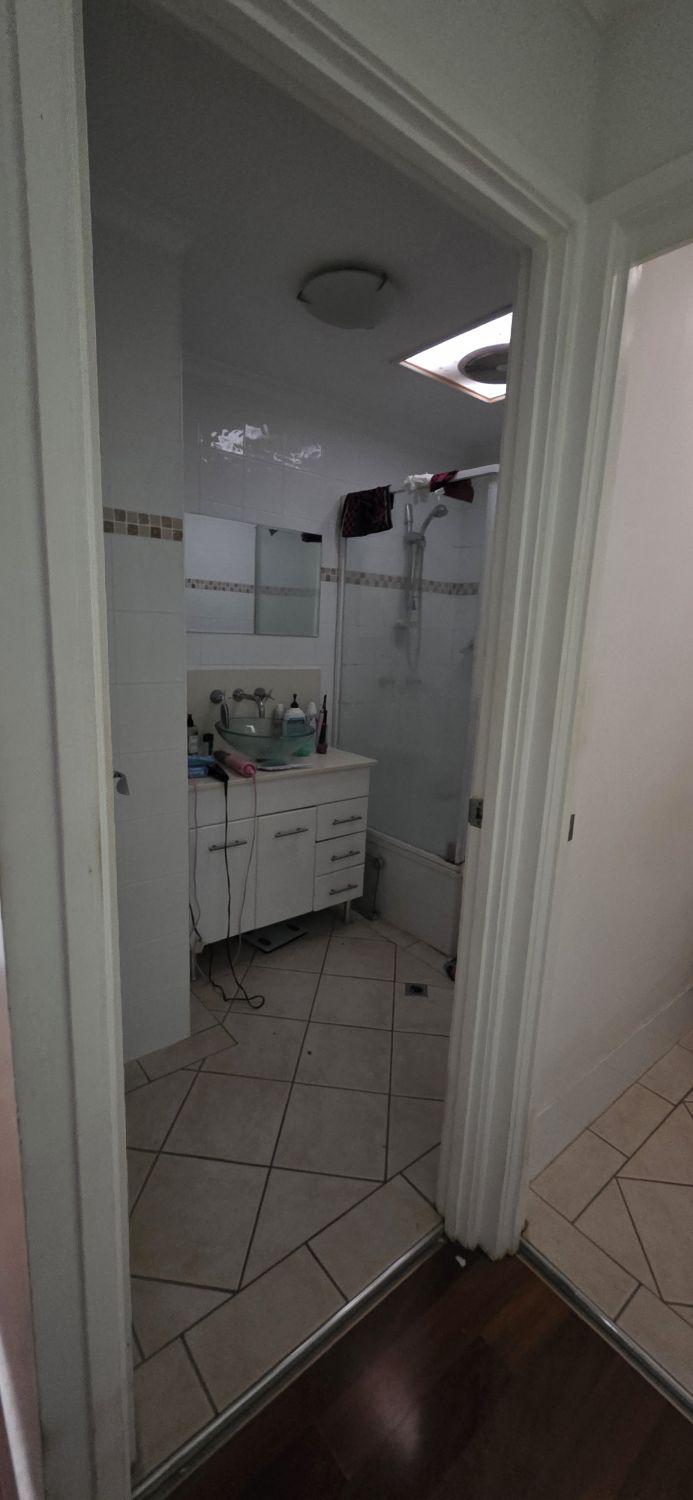 Holland Park bathroom entrance before renovation with compact vanity and enclosed shower