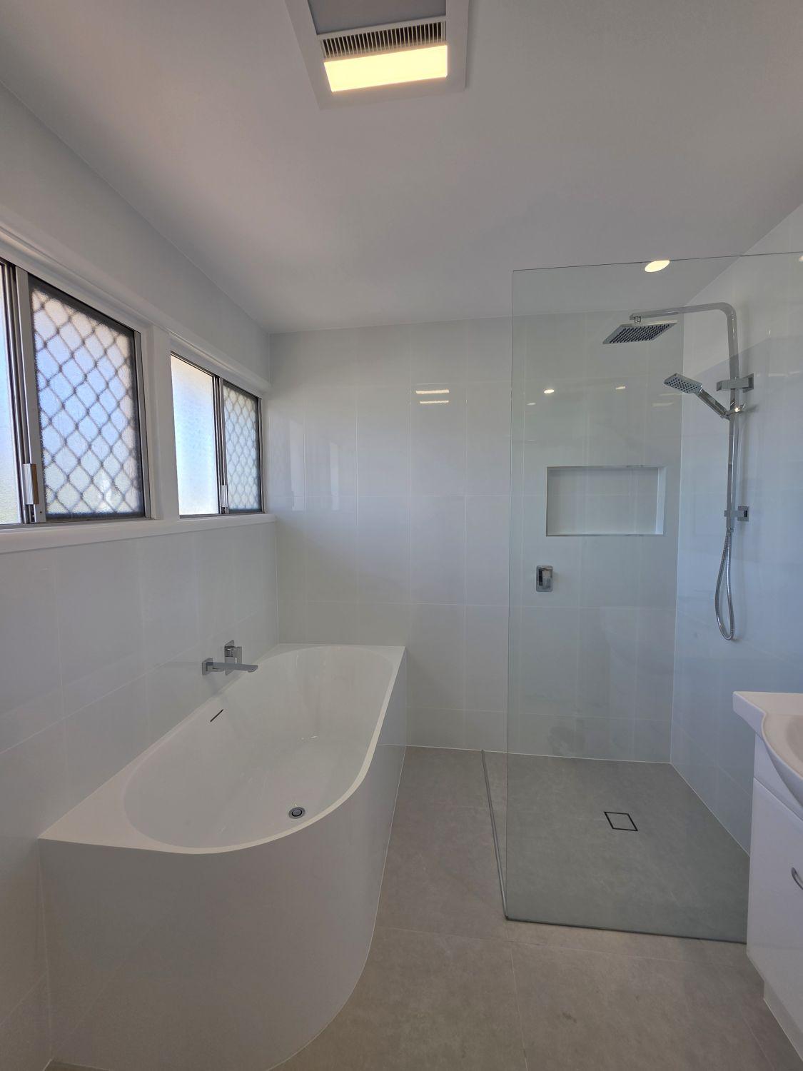 Modern bath beside the open shower in the completed Inala bathroom