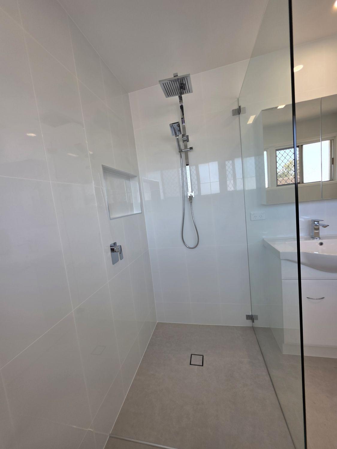 Open glass shower with rain head and niche in the completed Inala bathroom