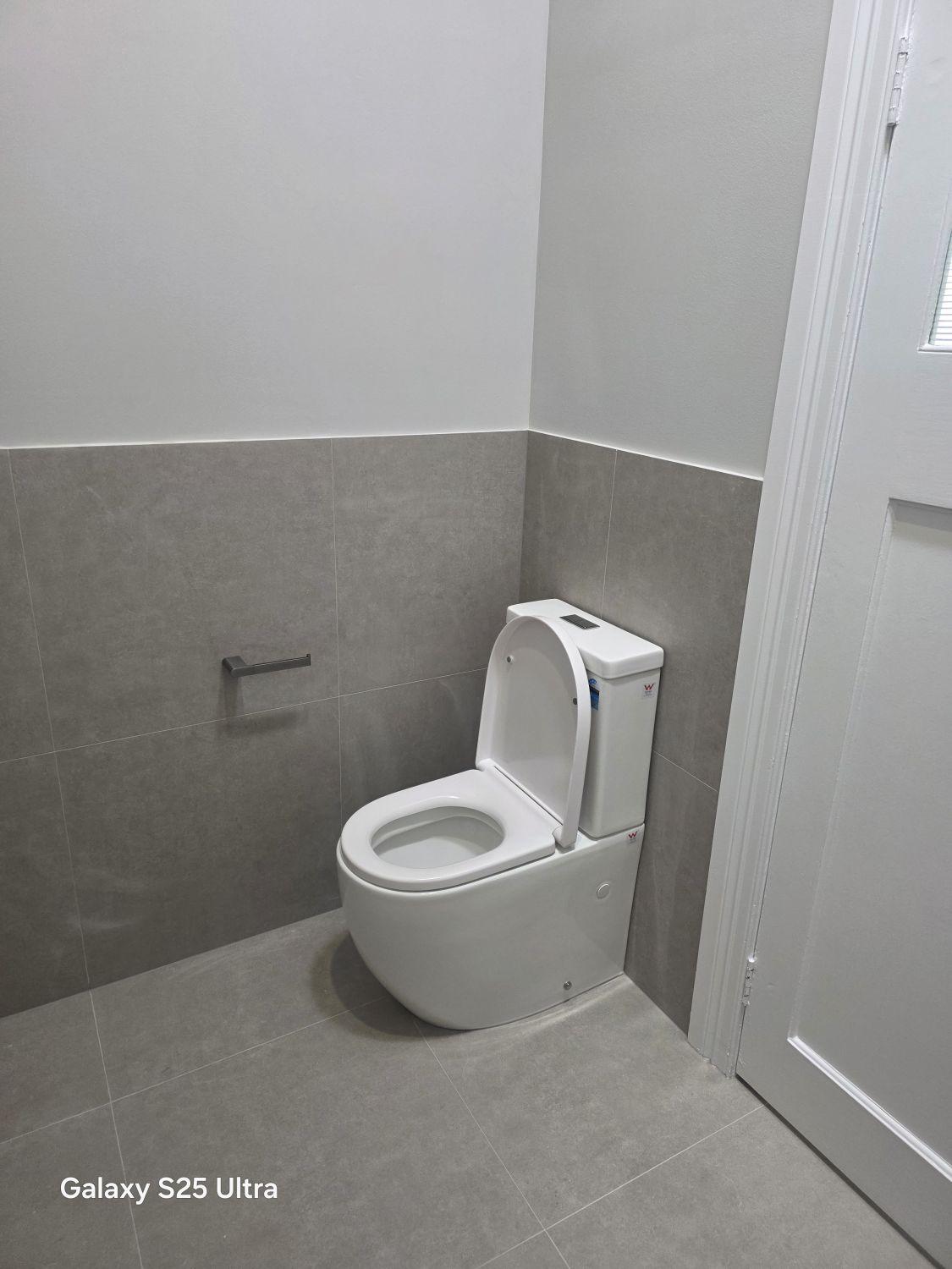Separate Kalinga toilet after renovation with grey wall and floor tiling