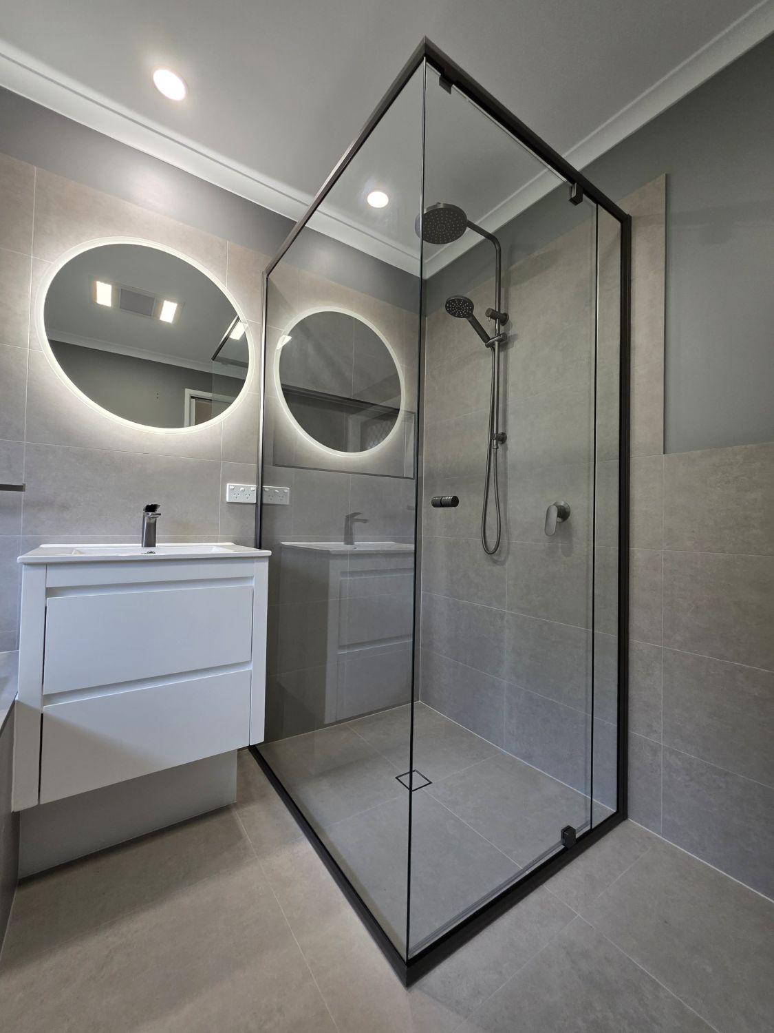 Floating vanity, illuminated mirror and black-framed shower in Karana Downs