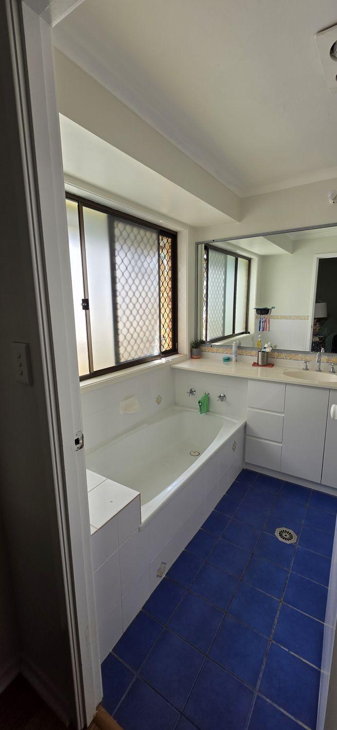 First Karana Downs bathroom before renovation with blue floor, built-in bath and vanity
