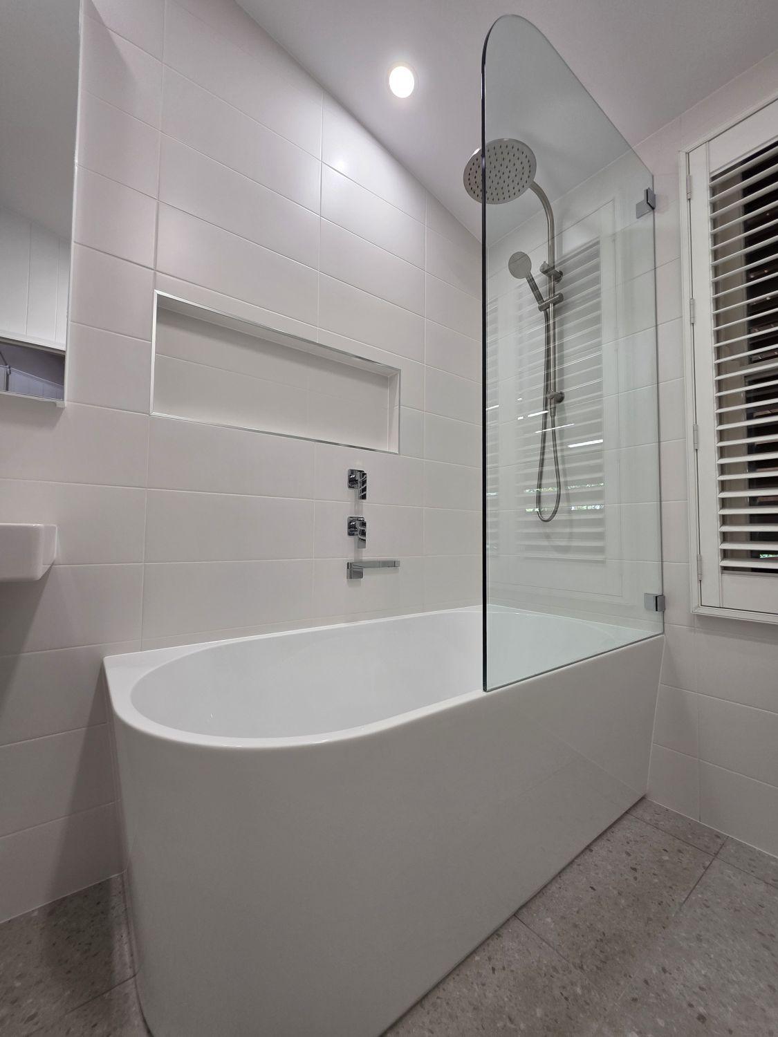 New curved bath with glass shower screen and recessed niche in Stones Corner