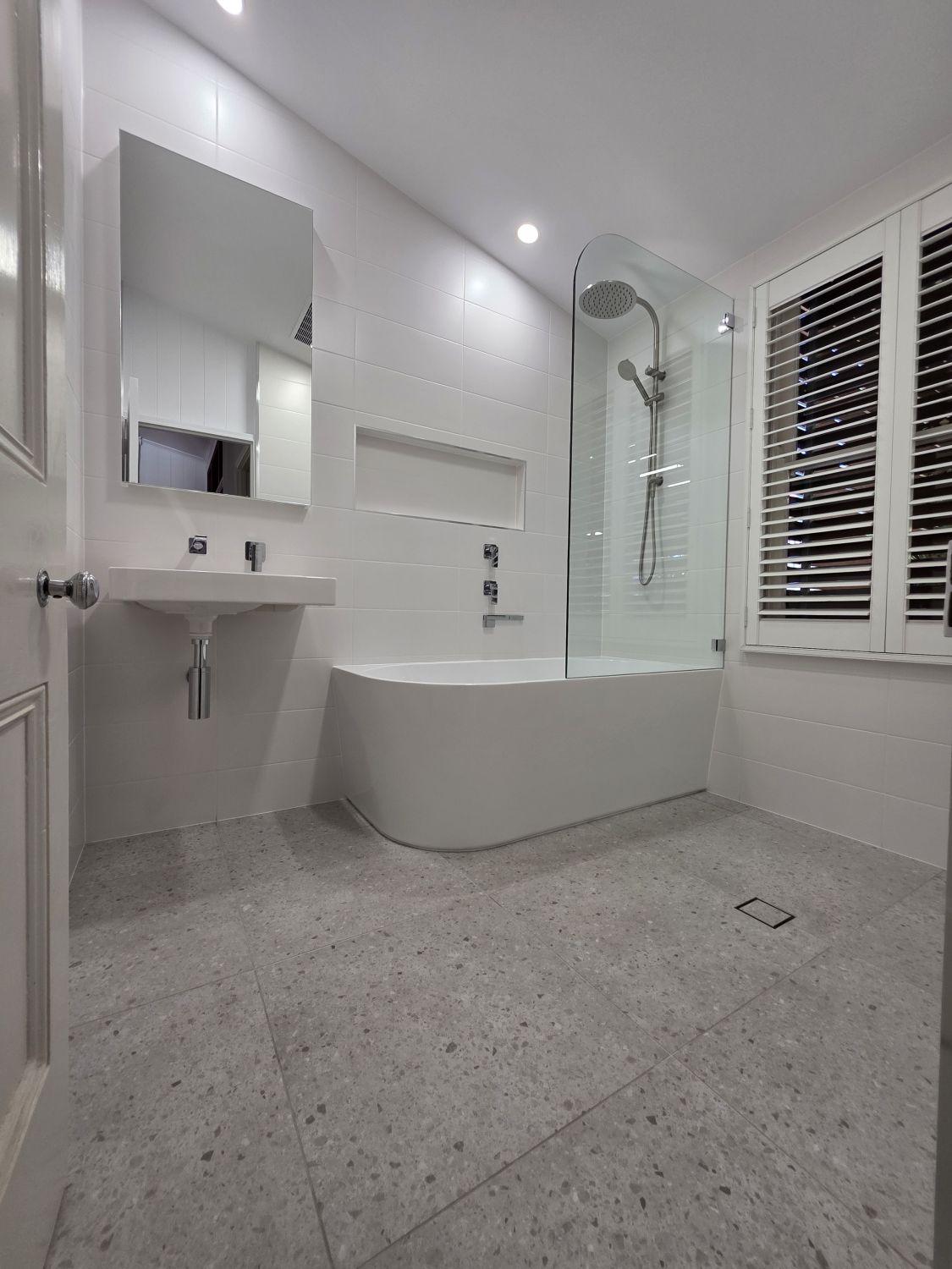 Stones Corner bathroom after renovation with wall-hung basin and curved bath