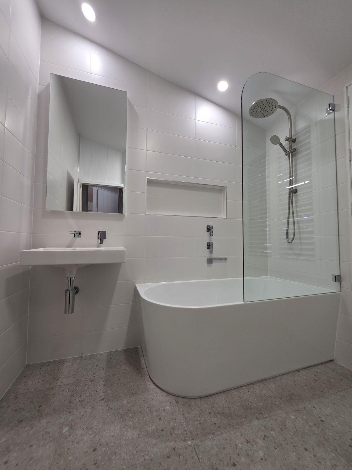 Finished Stones Corner bathroom with bath, basin and glass shower screen