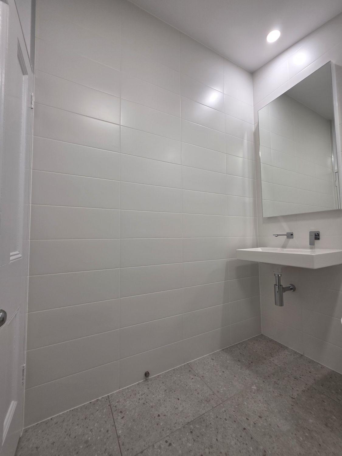 Full-height white tiling and wall-hung basin in the finished Stones Corner bathroom